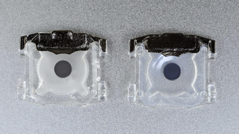 The previous generation of MacBook Pro keys (left) has a foggy silicone membrane, while the new generation (right) has a smooth, transparent membrane.